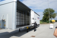 Užuolaidinė puspriekabė su patobulintu atidarymo mechanizmu